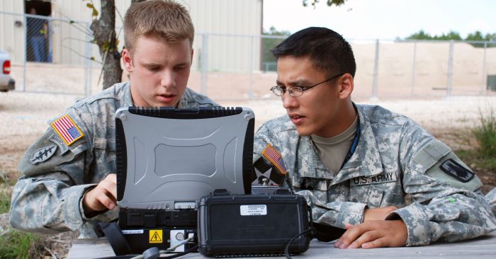 Two men in army fatigues looking at a government laptop