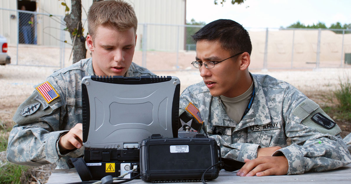 Two men in army fatigues looking at a government laptop