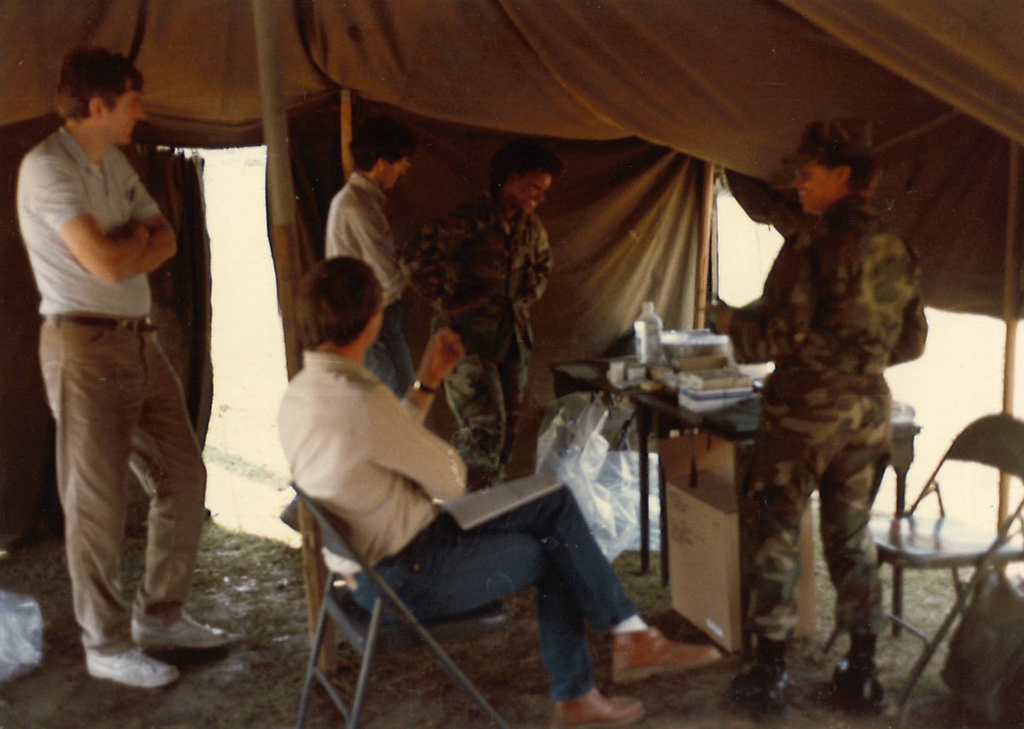 Image of researchers and members of the army in a tent talking to each other
